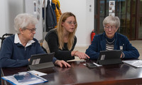 2 ältere Frauen bekommen von einer jüngeren Frau den Umgang mit dem Tablet erklärt.