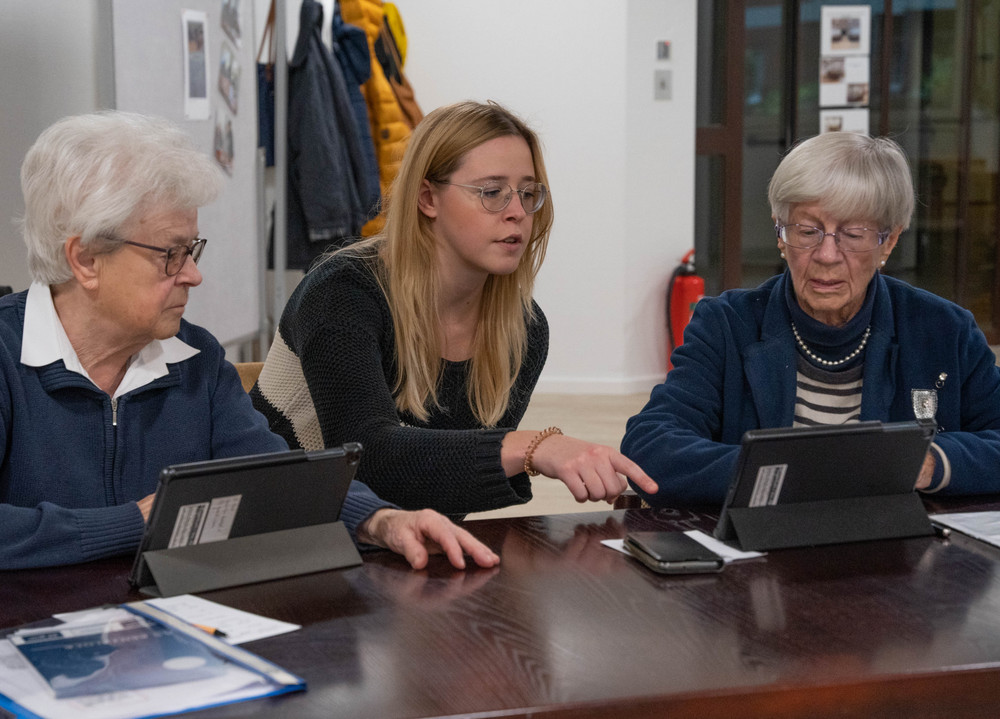 2 ältere Frauen bekommen von einer jüngeren Frau den Umgang mit dem Tablet erklärt.