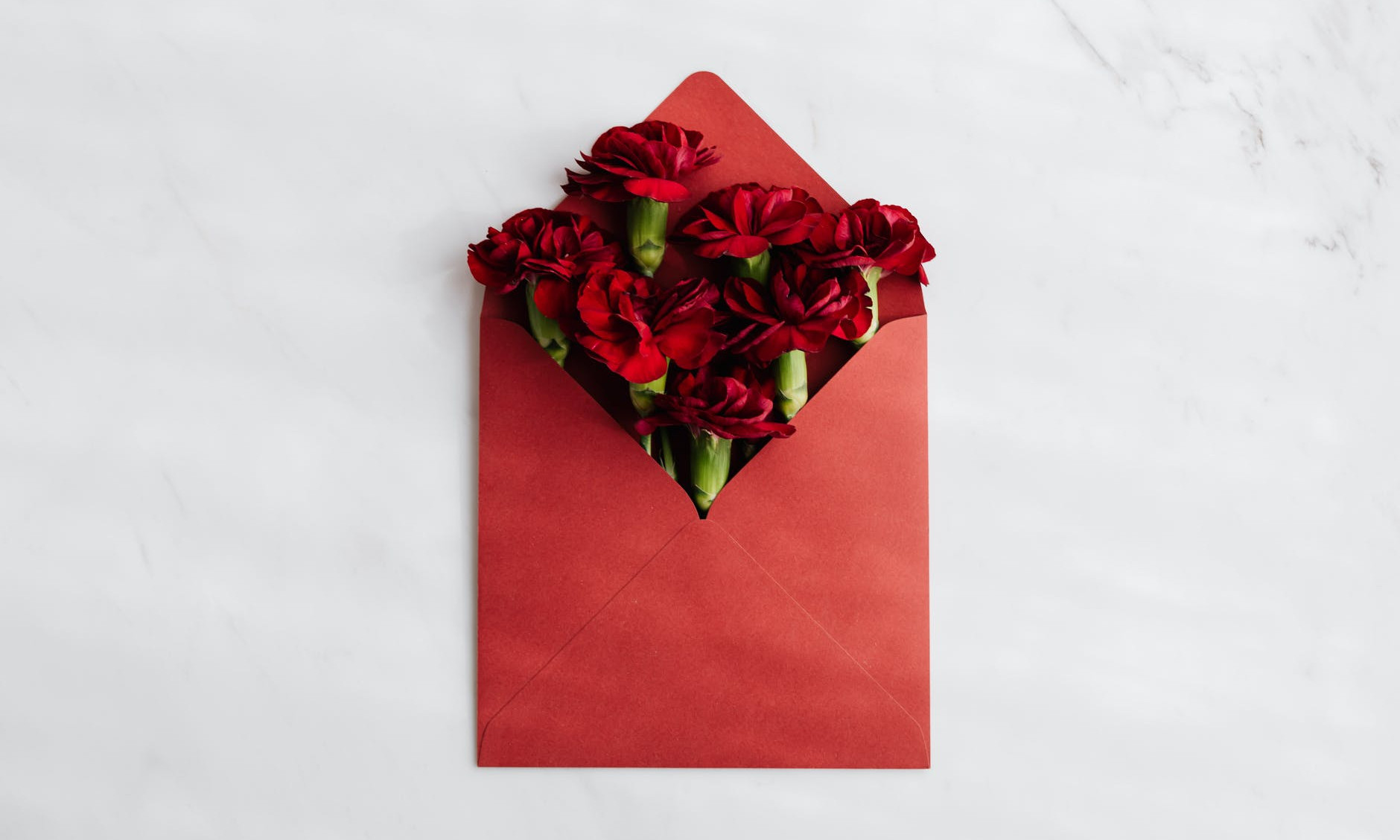 Ein Bild zeigt einen roten Umschlag, der mit Blumen gefüllt ist. Dies soll Anerkennung und Wertschätzung widerspiegeln