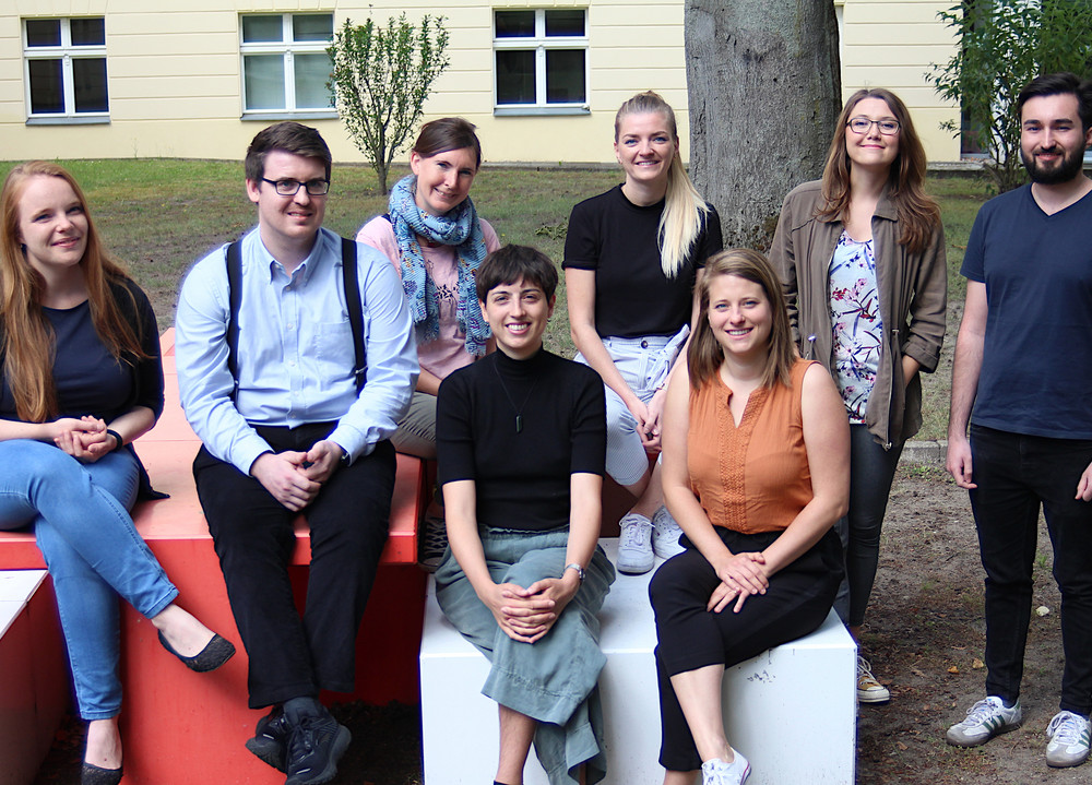 Ein Foto von 8 Personen im grünen Hinterhof des DRK-Gebäudes.