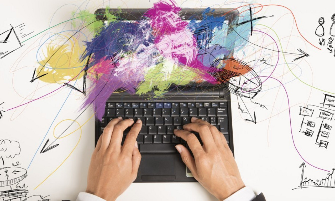 Hände auf einem Laptop hinterlegt mit Regebogenfarben.