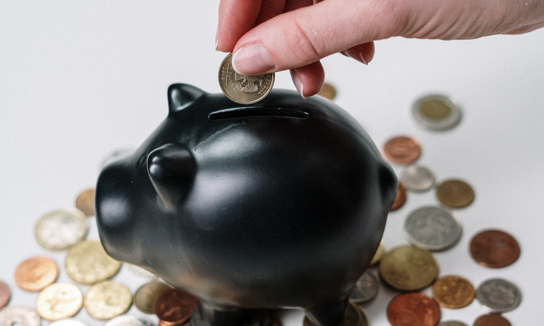 Das Bild zeigt ein Sparschwein, in das Kleingeld geworfen wird. So wird eine Assoziation mit dem Thema Finanzen, Überschuldung und Schuldnerberatung hergestellt.