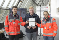 Drei Personen des Rettungsdienst halten eine Urkunde gemeinsam fest.