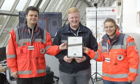 Drei Personen des Rettungsdienst halten eine Urkunde gemeinsam fest.