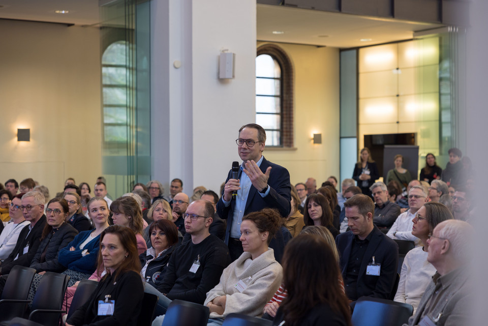 Ein Teilnehmer steht im Plenum des WFK 2025 und stellt eine Frage