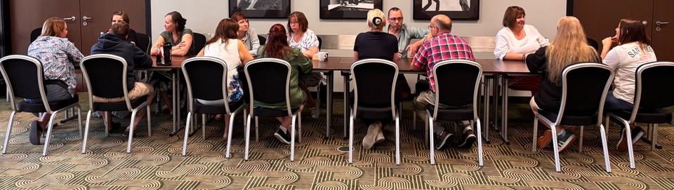 Gruppenfoto Modellkitas Eine Gruppe von Menschen sitzt an einem langen Tisch zusammen