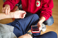 DRK-Helfer misst kniend den Puls einer Seniorin