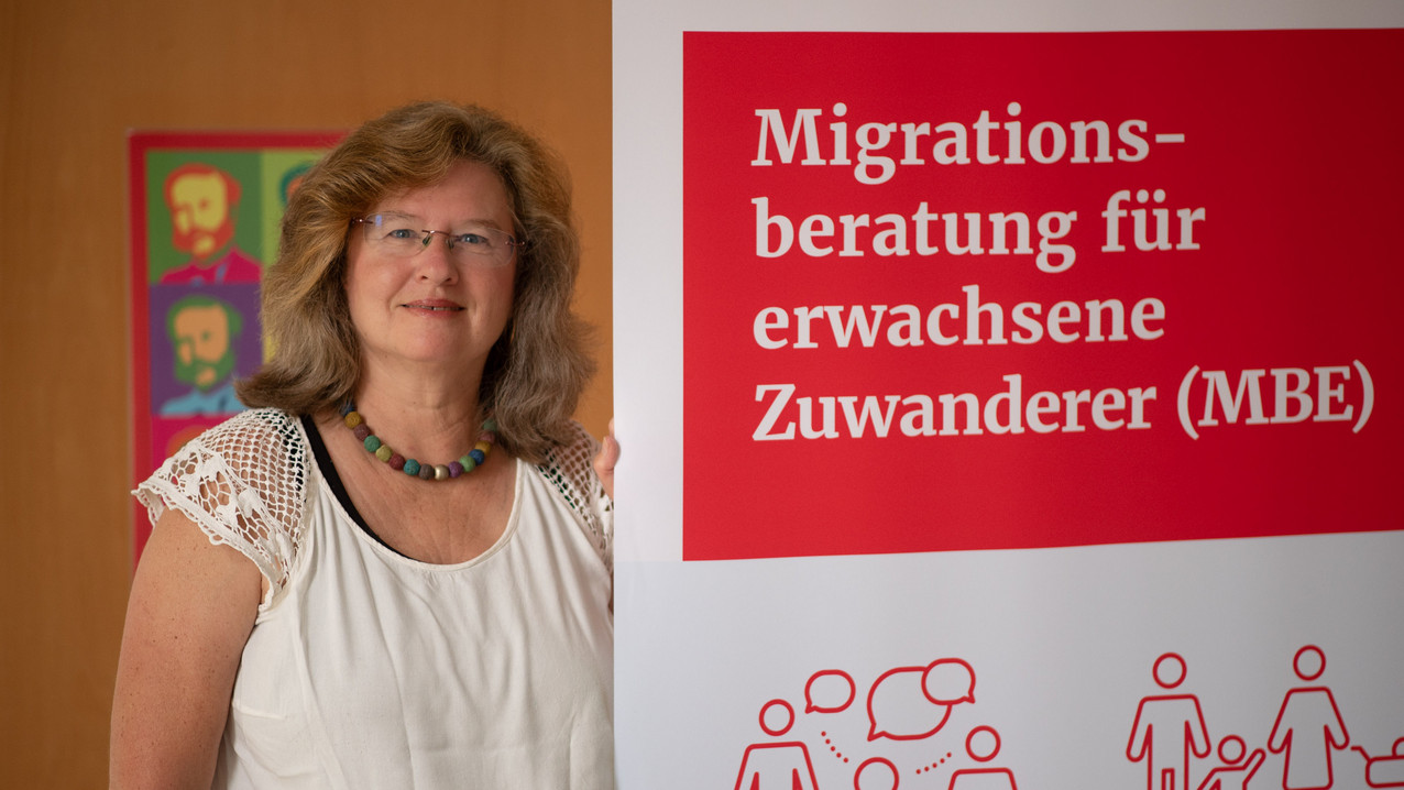 Migrationsberaterin Natalie Ammon neben einem MBE-Aufsteller