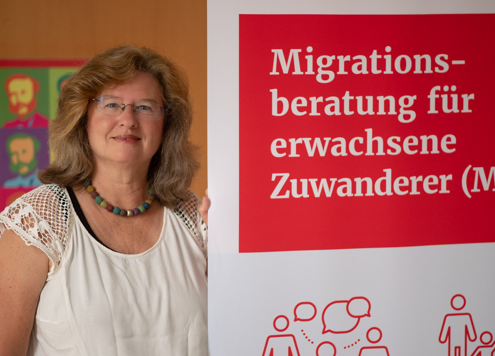 Migrationsberaterin Natalie Ammon neben einem MBE-Aufsteller