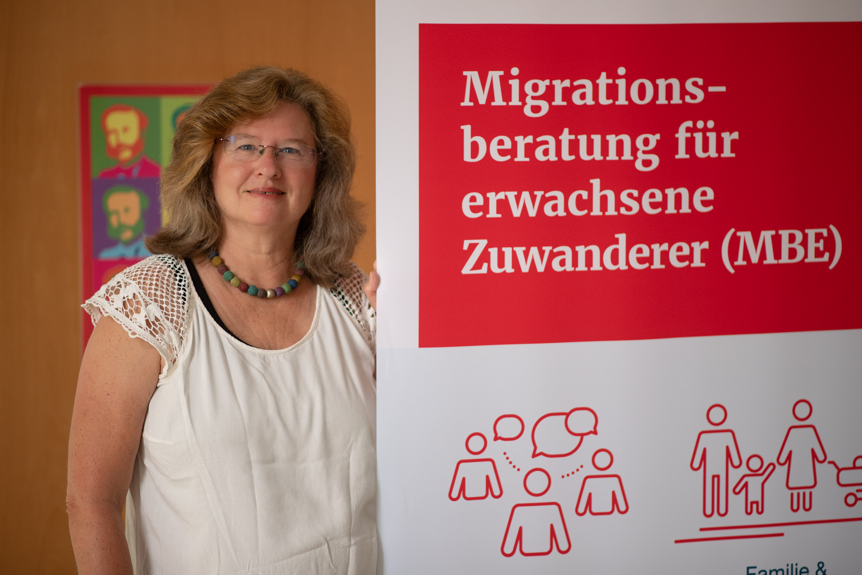 Migrationsberaterin Natalie Ammon neben einem MBE-Aufsteller