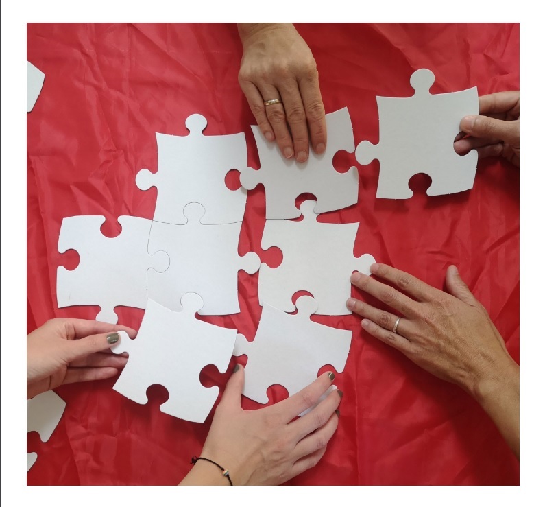 Fünf Hände setzen ein Puzzle zusammen